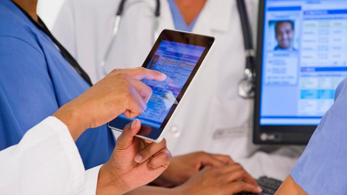 A doctor points at an EHR on a tablet