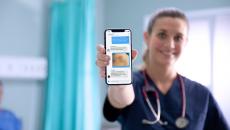 A nurse holding a mobile phone showing the Celo Health app