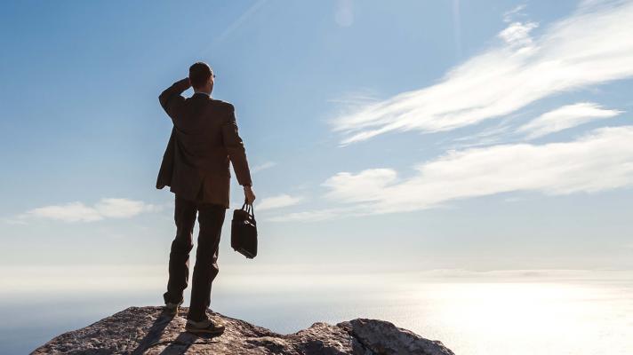 Businessperson looking out from a mountaintop