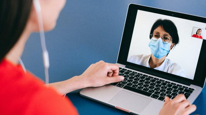 A patient speaks with a doctor via laptop